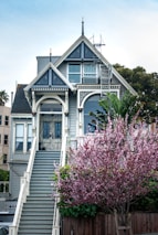 white and gray wooden house near pink flowers