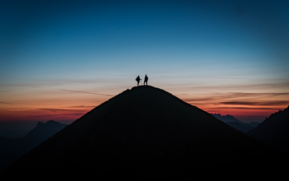 silhouette of person standing on top of mountain during daytime