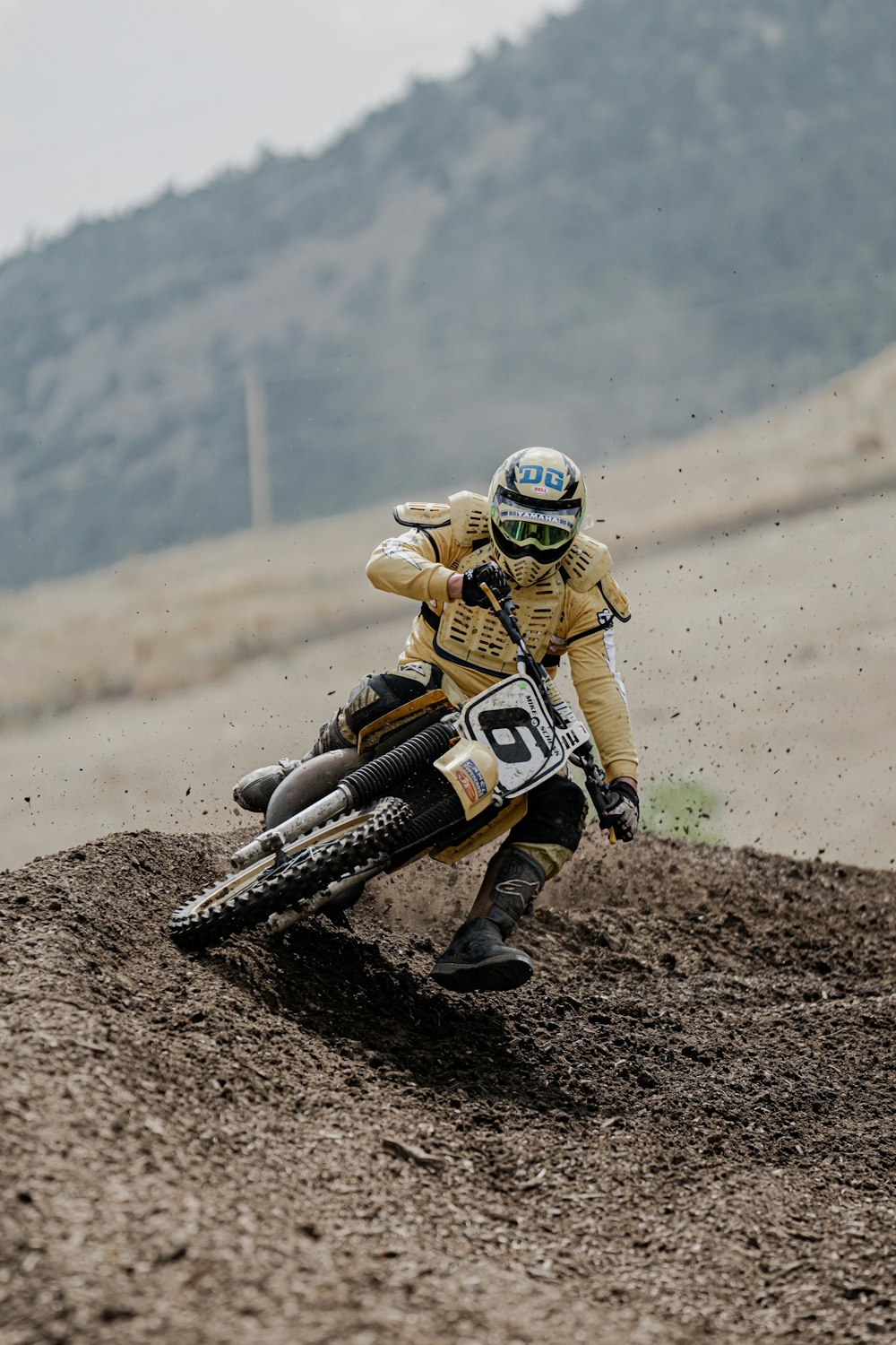 man in black and white suit riding motorcycle on brown dirt road during daytime