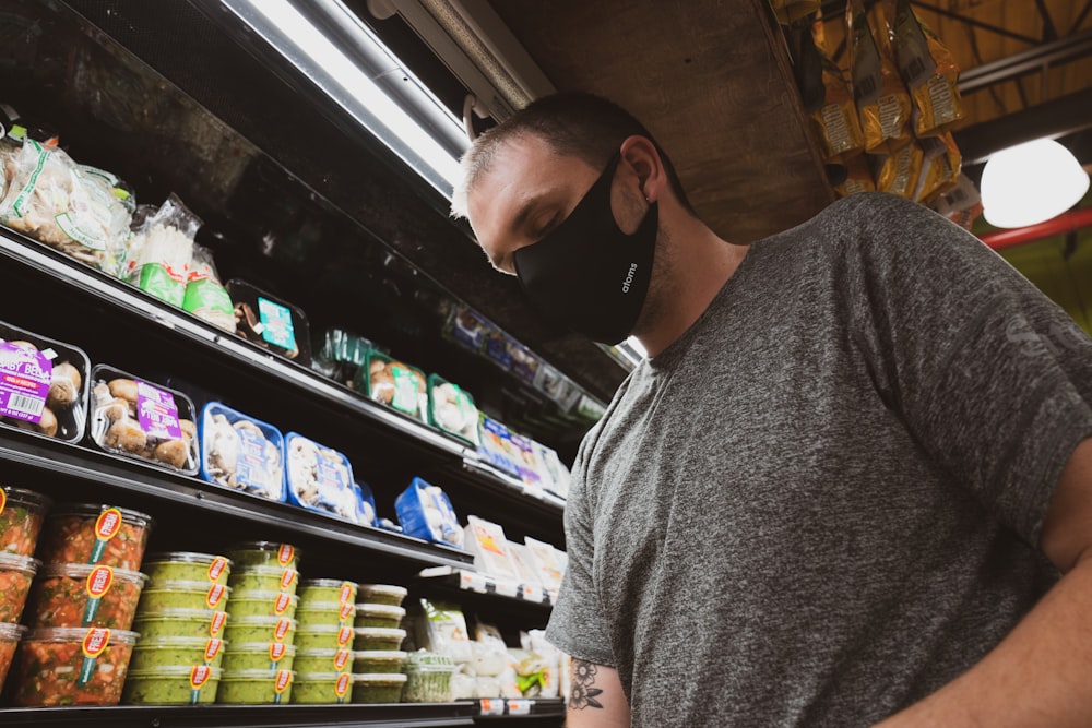 man in gray crew neck t-shirt standing near shelf