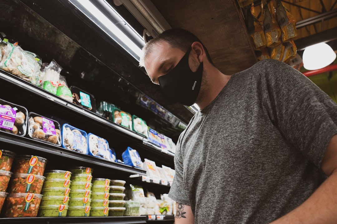 man in gray crew neck t-shirt standing near shelf,