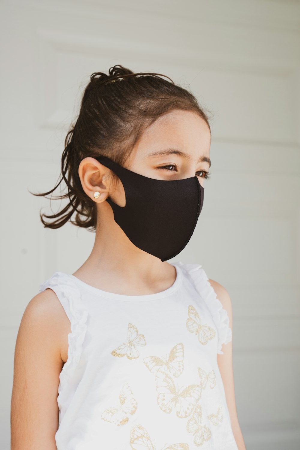 woman in white floral tank top wearing black mask