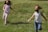 Happy children running barefoot on soft, natural grass carpet in a sunny garden.