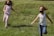 Happy children running barefoot on soft, natural grass carpet in a sunny garden.