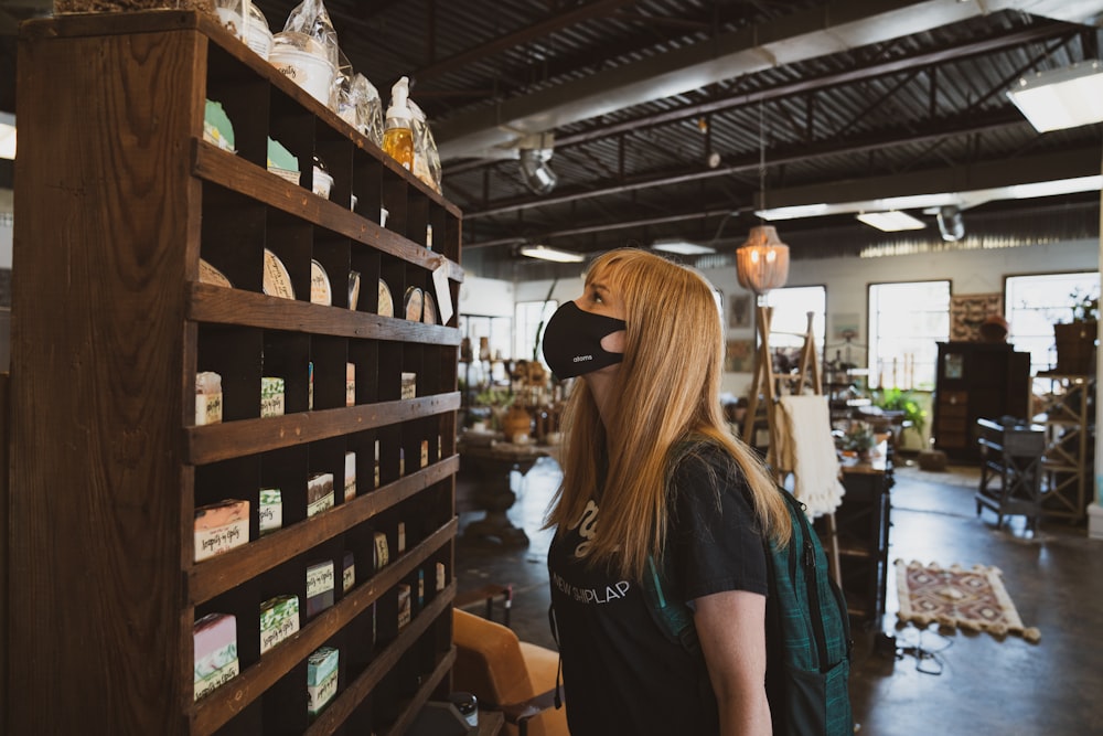 woman in black t-shirt standing near brown wooden shelf