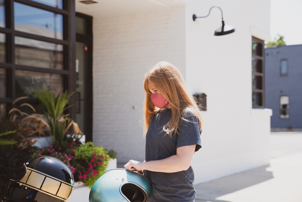 woman in blue crew neck t-shirt and blue denim shorts holding green and silver helmet