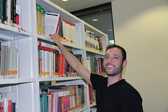 A smiling student holding books in a classroom filled with colorful posters.