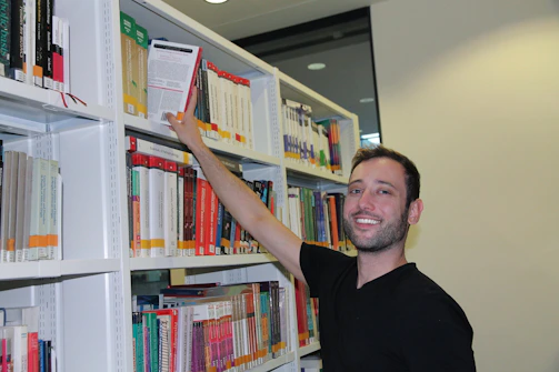 A smiling volunteer packing donated books into a box ready for delivery.