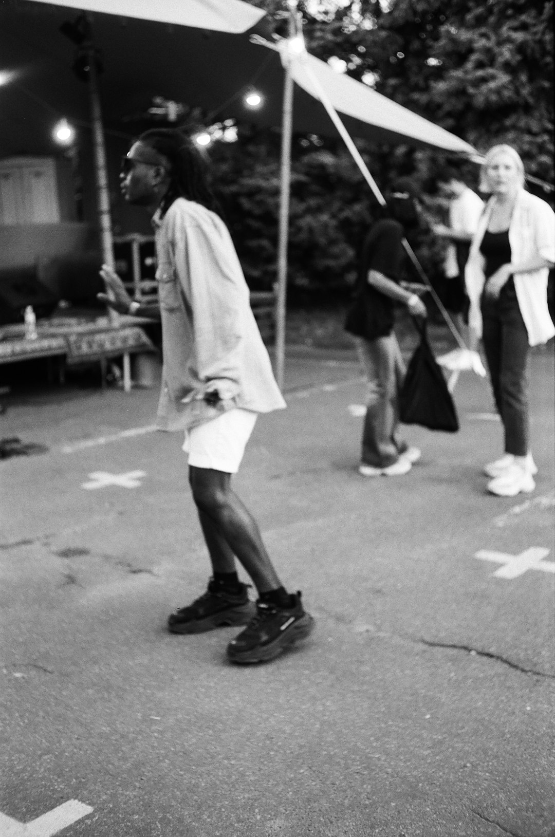 man in white t-shirt and black shorts walking on street