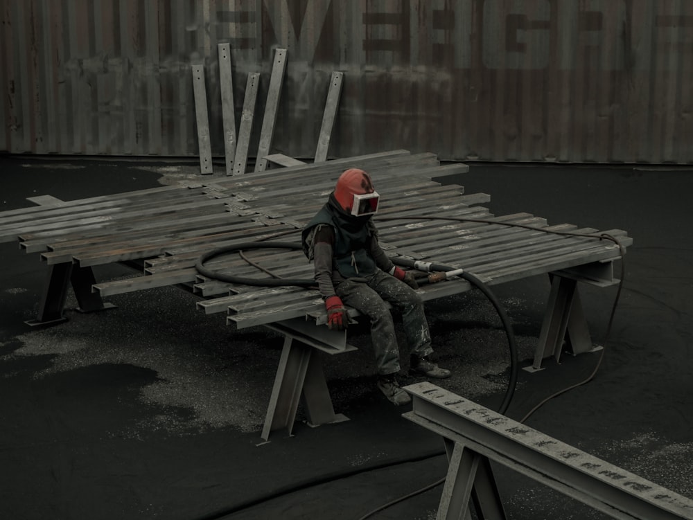 man in black jacket and red helmet sitting on brown wooden bench