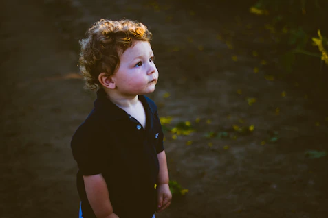 girl in black polo shirt standing on brown soil during daytime
