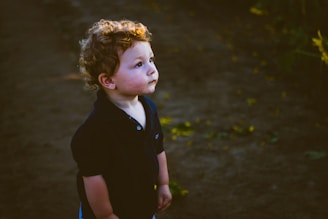girl in black polo shirt standing on brown soil during daytime