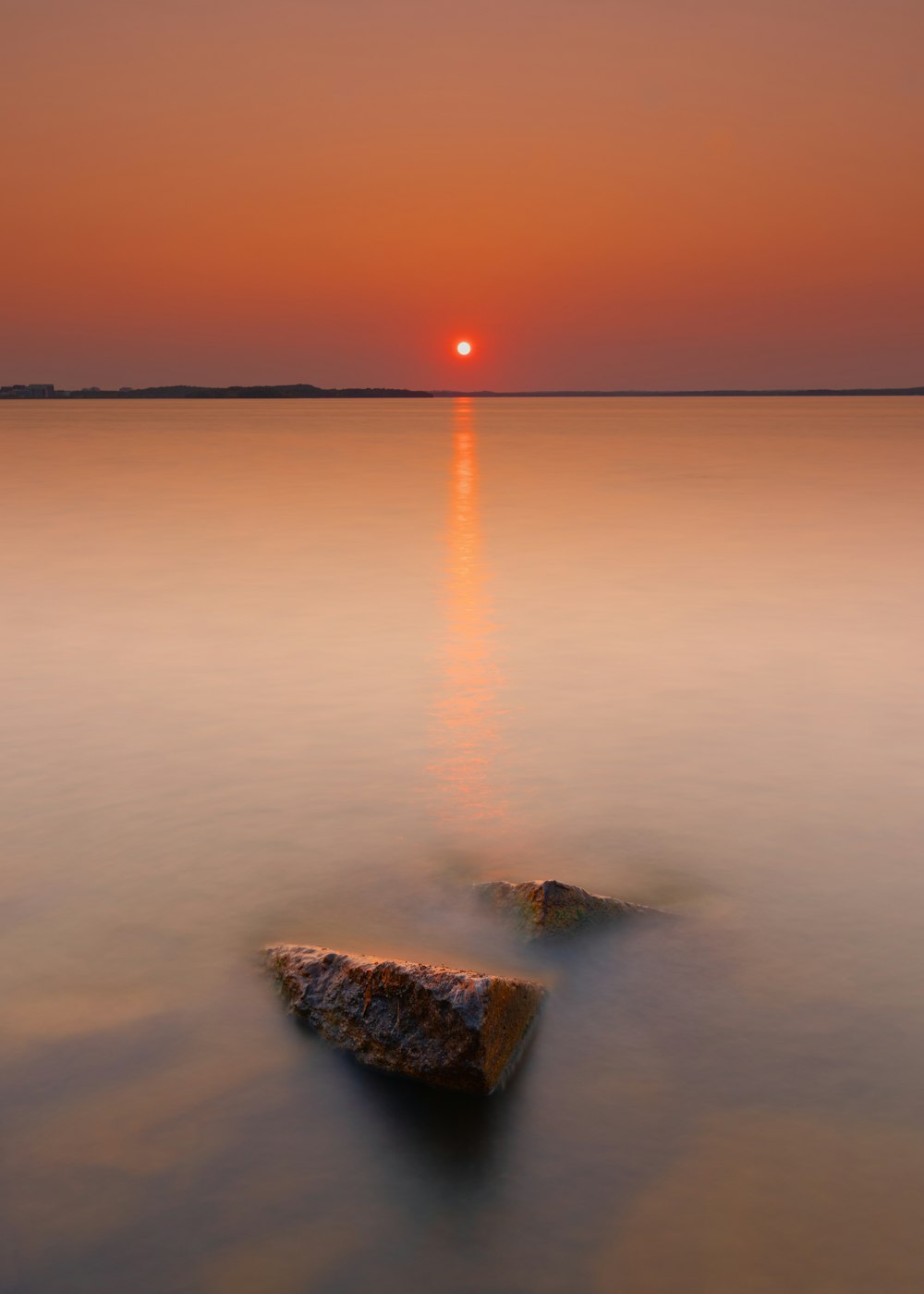 日没時の水域の茶色の岩層