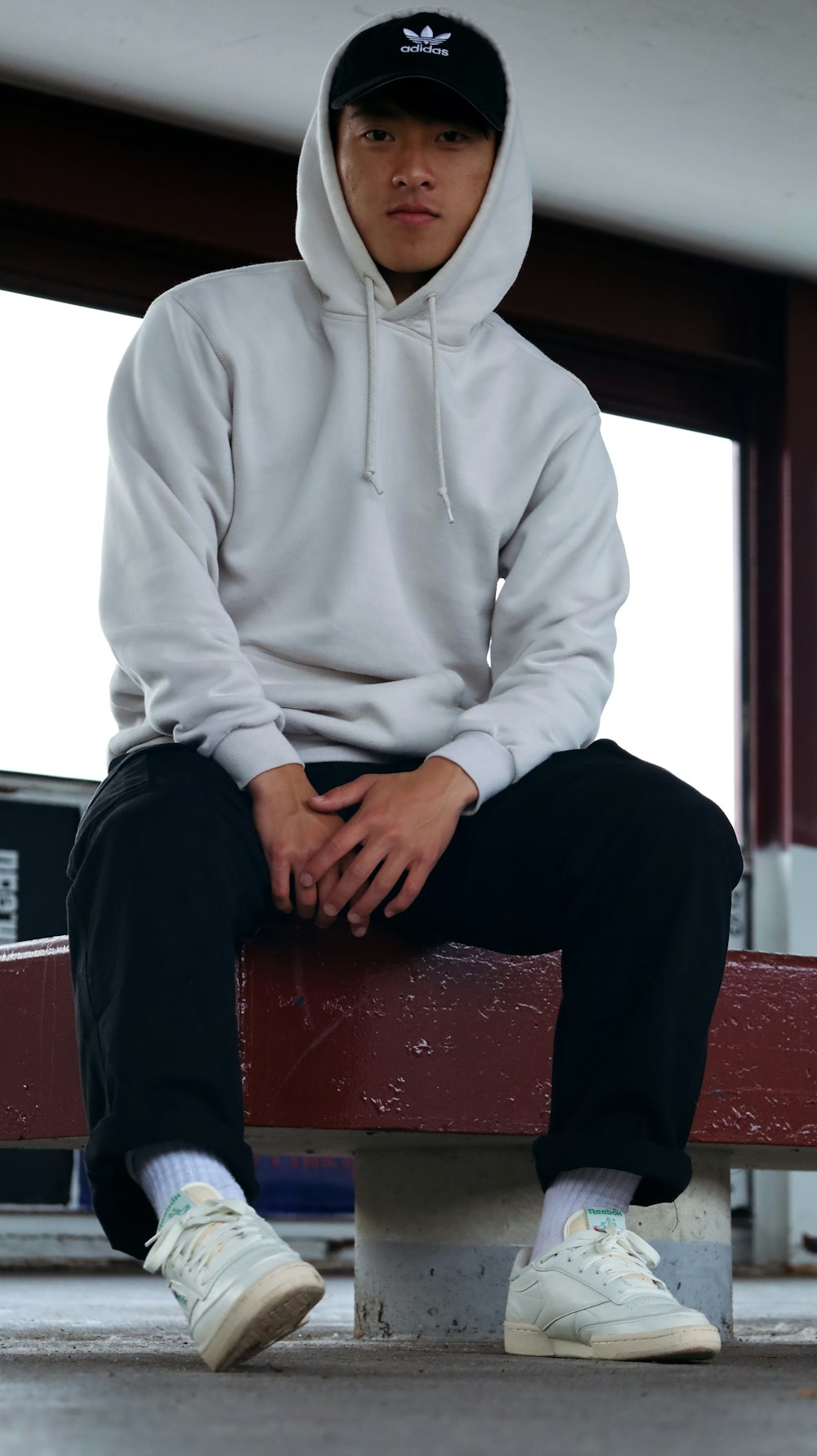 man in white hoodie sitting on red sofa