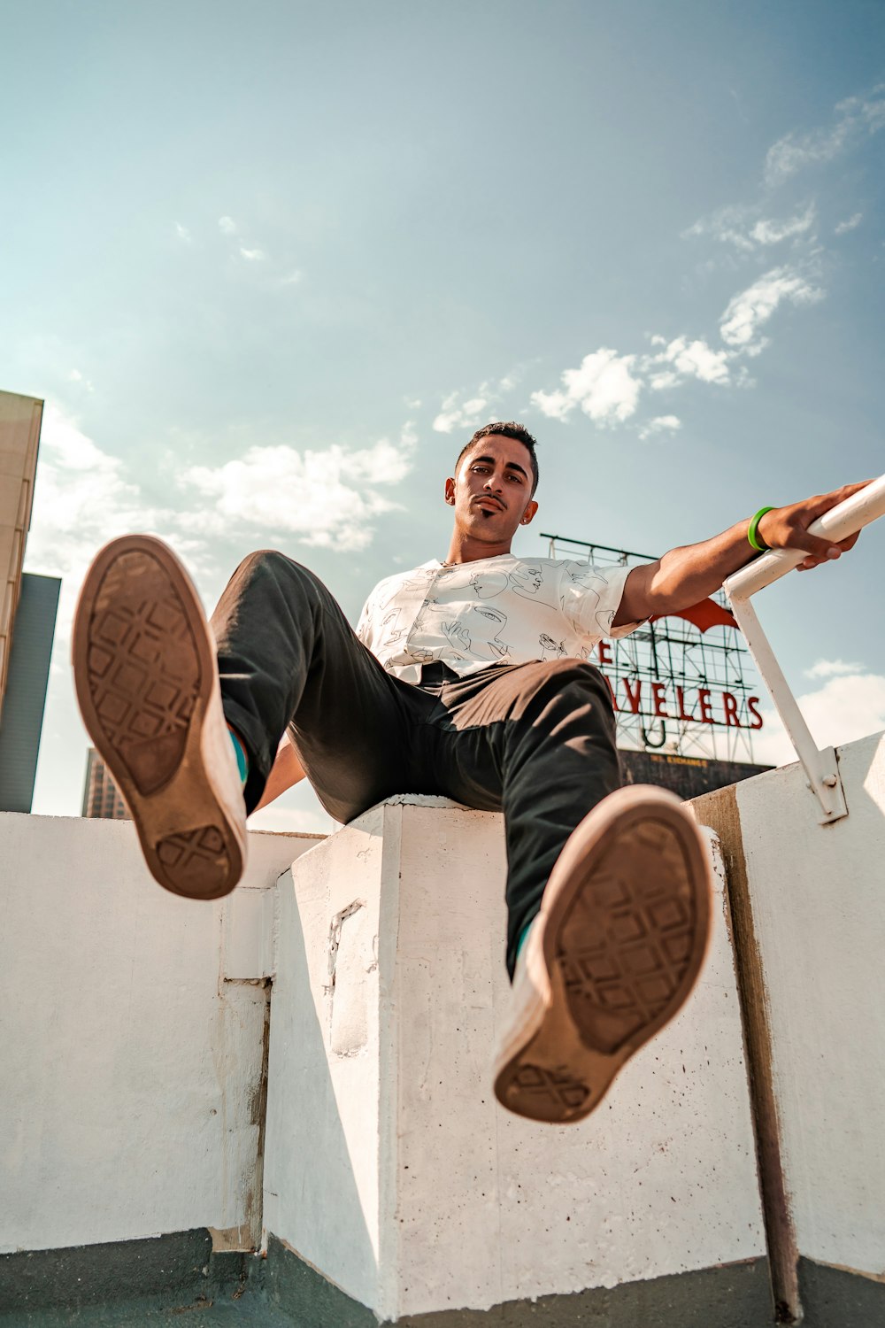 man in white shirt and blue denim jeans sitting on white concrete bench during daytime