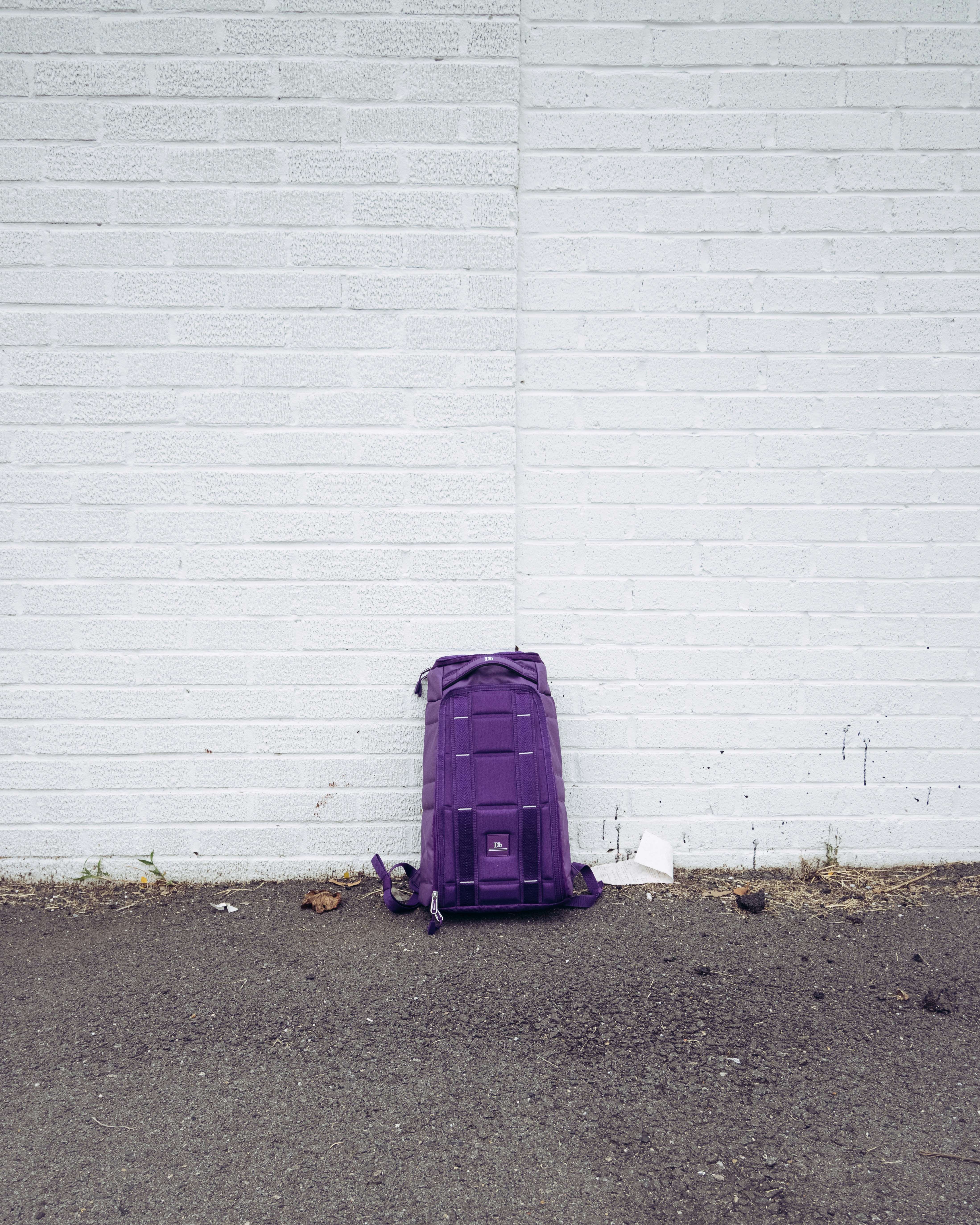 purple luggage bag beside white wall