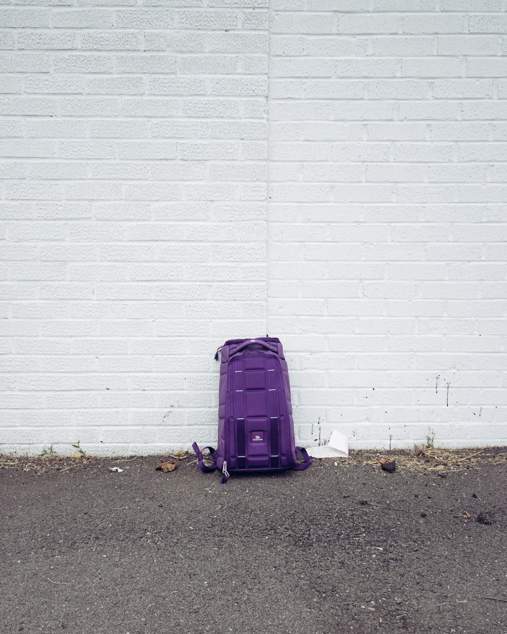 purple luggage bag beside white wall