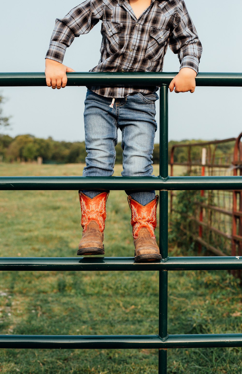 person in blue denim jeans and brown leather cowboy boots sitting on black metal railings during