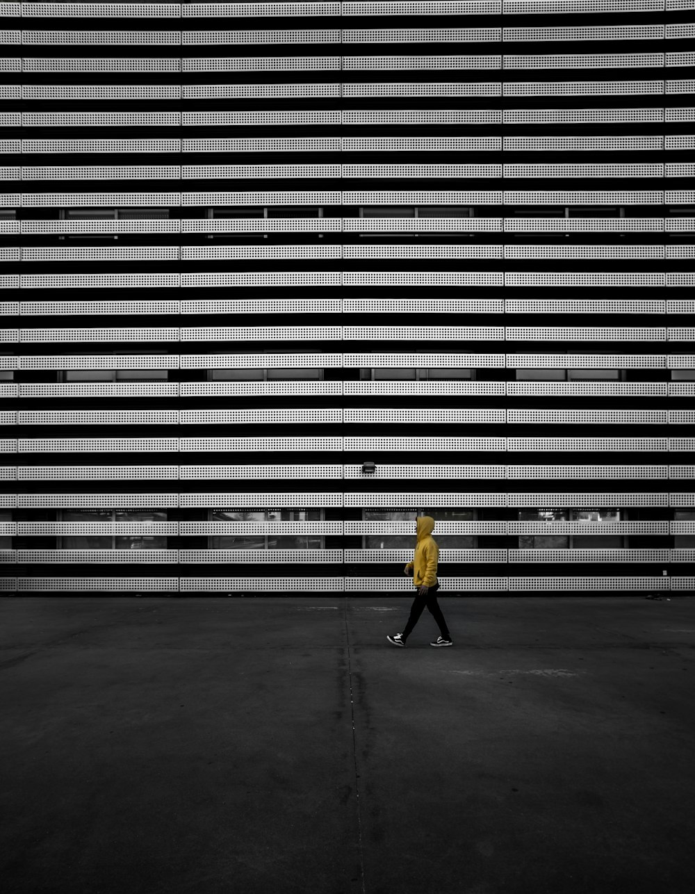 person in black jacket walking on gray concrete pavement