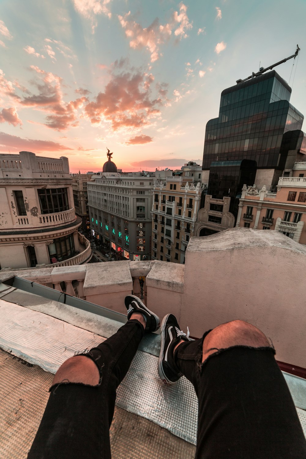 person in black and white sneakers sitting on concrete wall