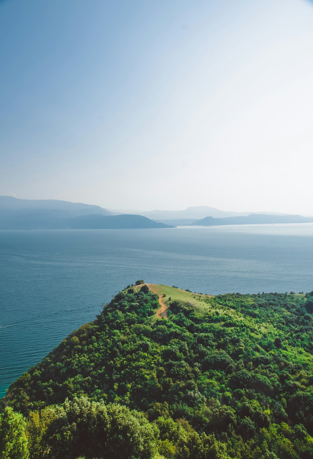 green grass covered mountain beside body of water during daytime