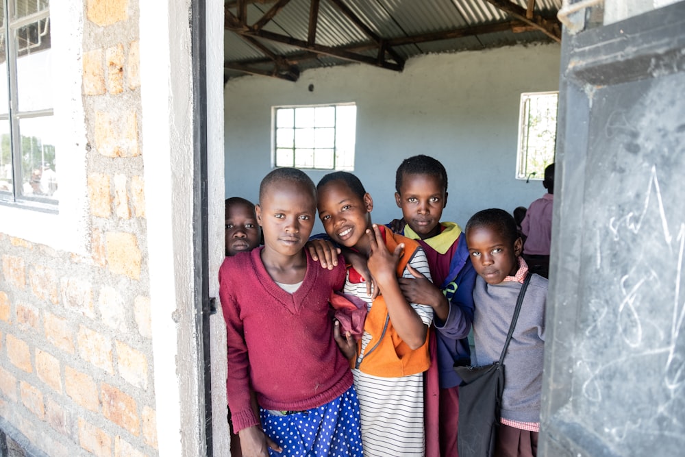 3 boys and girl standing near door