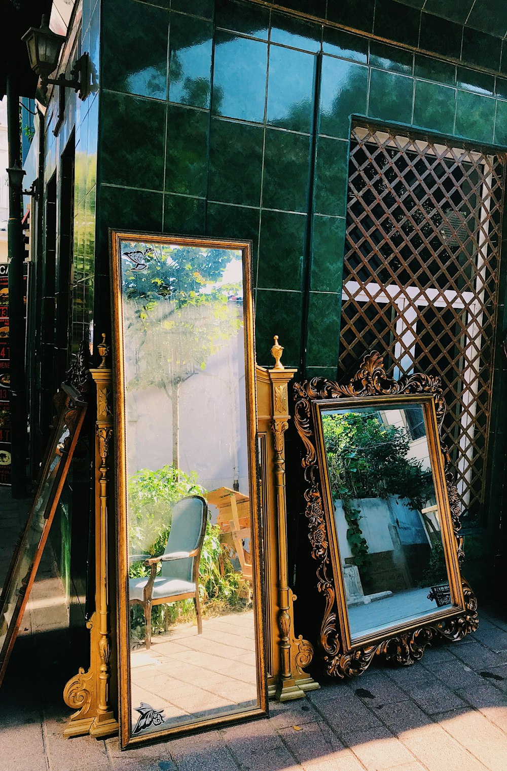 brown wooden framed mirror on green and white wall tiles