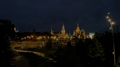 A nighttime cityscape featuring iconic university buildings illuminated against the sky.