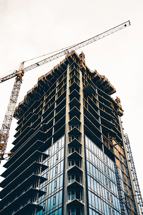 Building under construction with a yellow crane against the sky