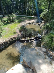 A peaceful zen garden with smooth stones and flowing water under sunlight.
