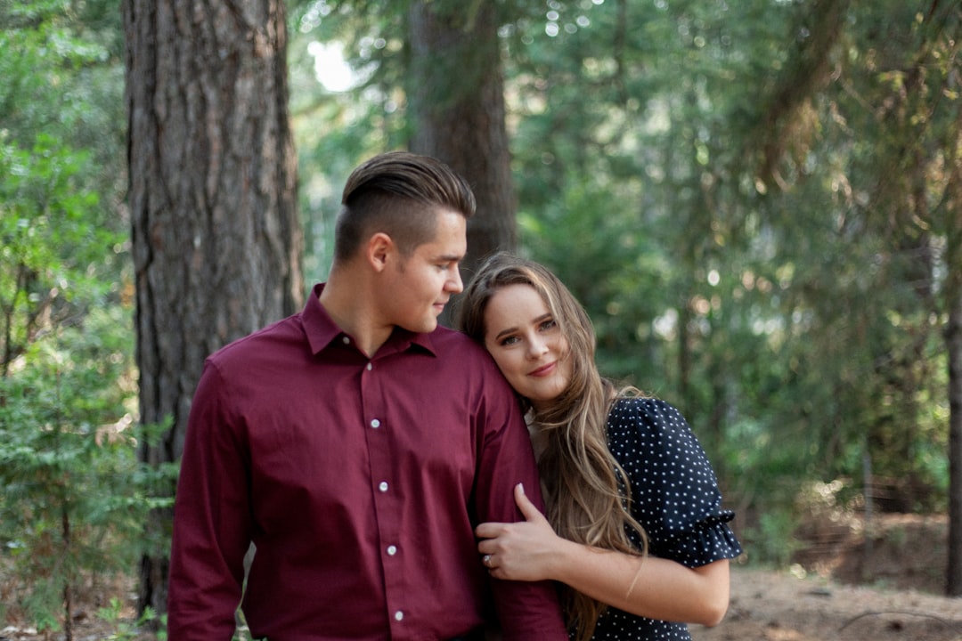 man in red dress shirt hugging woman in black and white polka dot dress