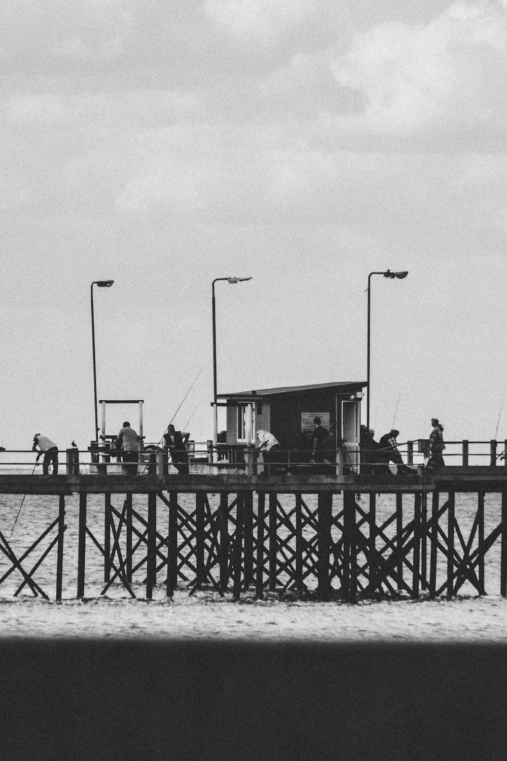 grayscale photo of people standing on bridge