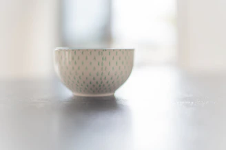 Close-up of a smooth, hand-thrown ceramic bowl with a deep green glaze catching soft natural light.