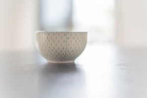 Close-up of a handcrafted green ceramic bowl with intricate patterns, glowing softly in natural light.