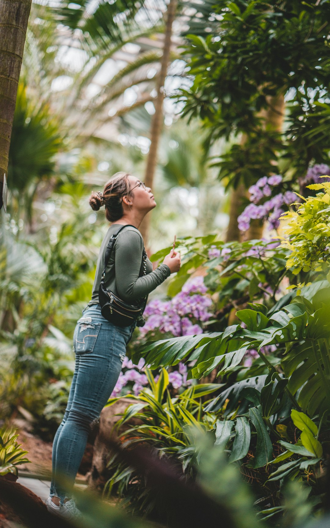 woman in black long sleeve shirt and blue denim jeans standing near green plants during daytime