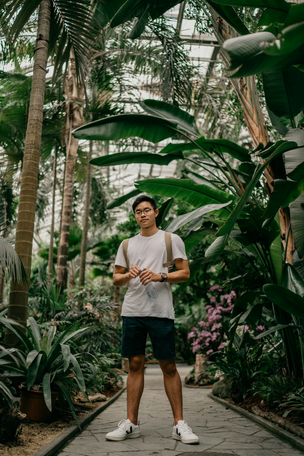 man in white crew neck t-shirt standing near banana plants during daytime