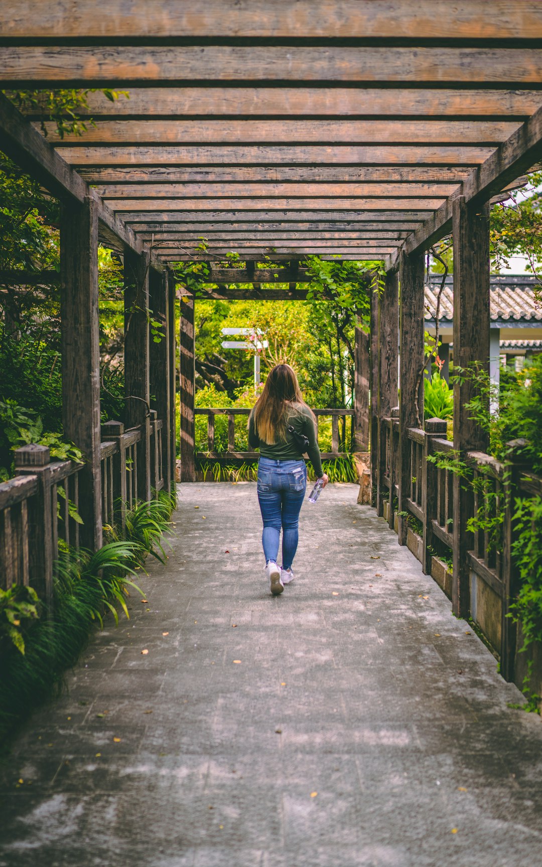 woman in blue denim jacket walking on pathway