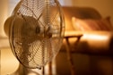 white stand fan turned on in room