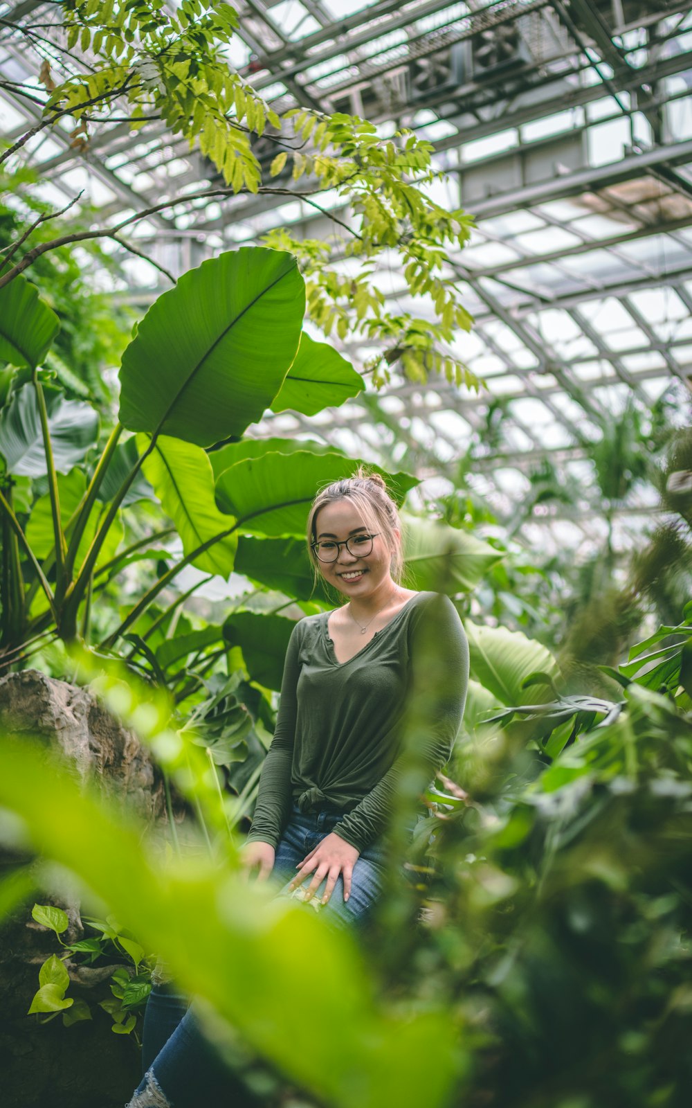 woman in black long sleeve shirt and blue denim jeans standing in front of green plants