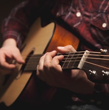 person playing brown acoustic guitar