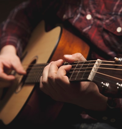 person playing brown acoustic guitar