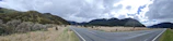 A wide shot of an open road winding through Montana-style mountains under a soft golden sky.