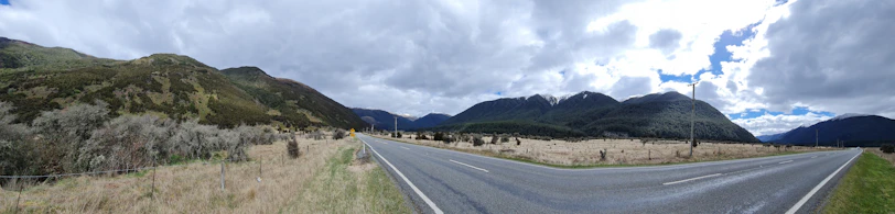 A wide shot of an open road winding through Montana-style mountains under a soft golden sky.