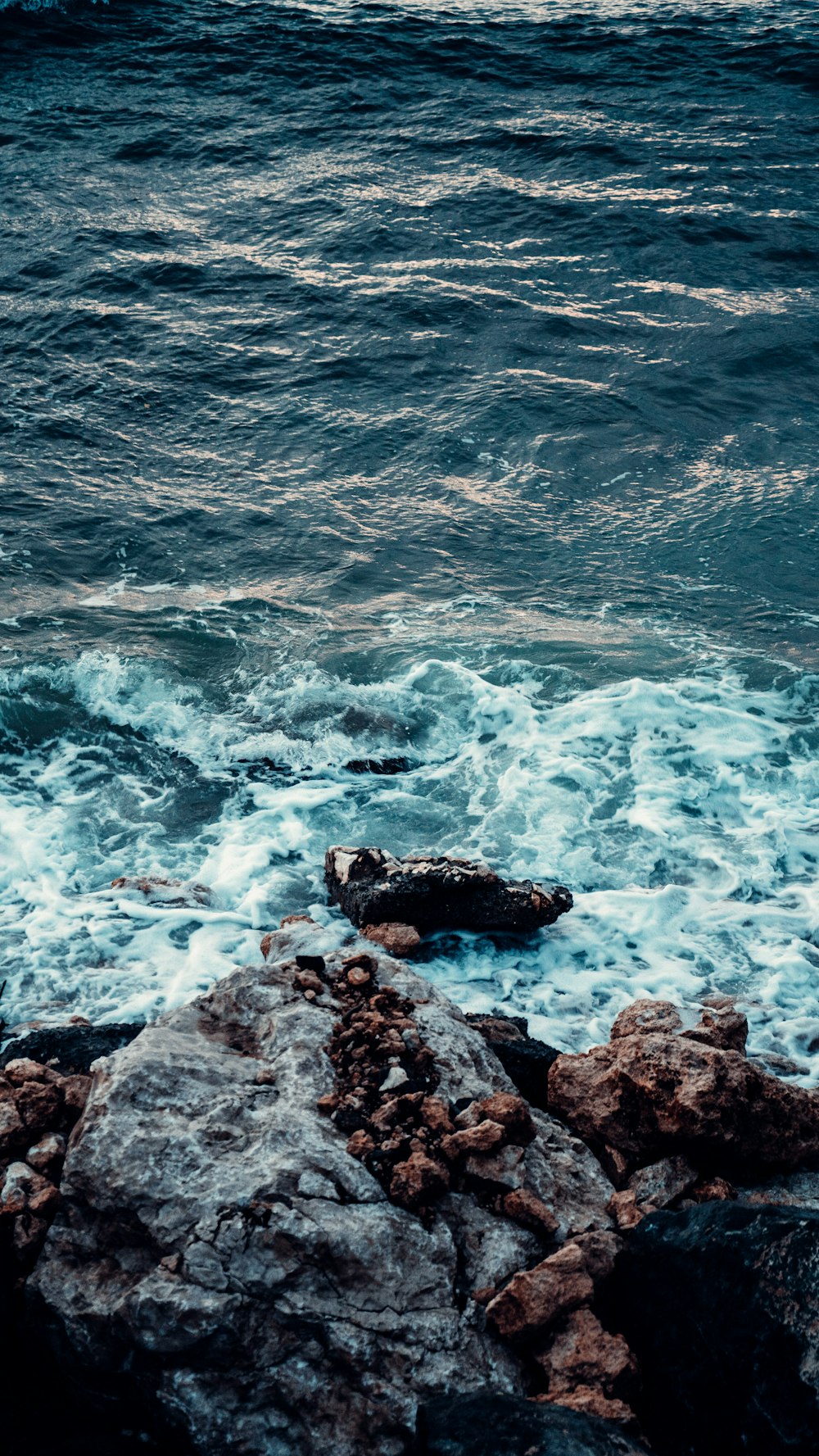 black rock formation on body of water during daytime