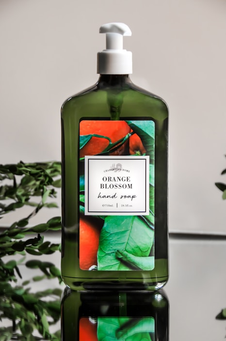 A bright bottle of liquid soap with fresh botanical ingredients around it