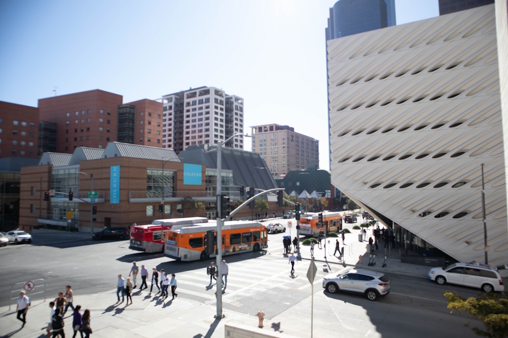 people walking on sidewalk near white and orange bus during daytime