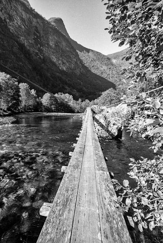 grayscale photo of wooden bridge over river in Flam Norway