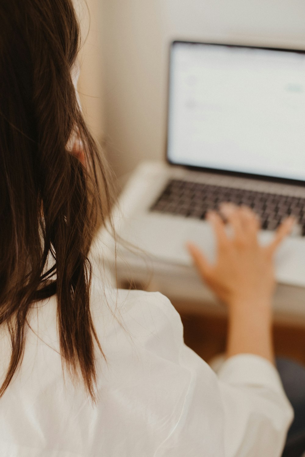 woman in white shirt using macbook pro