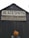 A weathered wooden building with a peaked roof features a large sign that reads 'BLACKSMITH' with additional text 'HUB CITY IRON WORKS' and 'BLACKSMITH SHOP-BOILER REPAIR'. A person with reddish hair stands in front of the dark, rustic door.