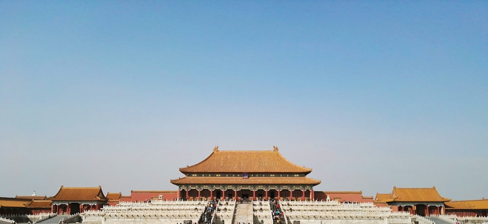 people walking on red and white concrete building under blue sky during daytime